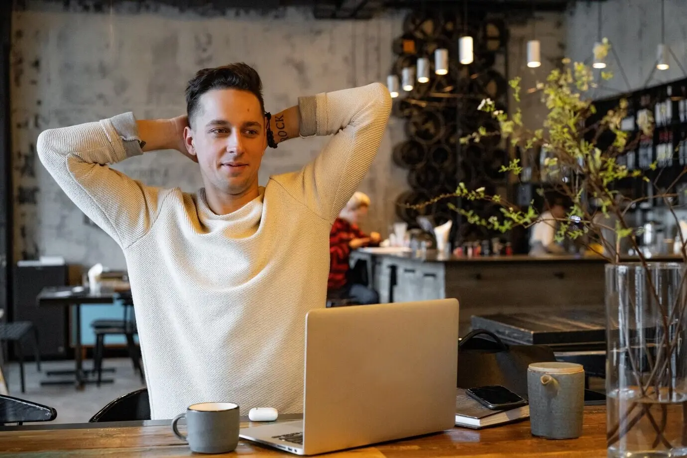 A young man in a café, drinking tea and working on a laptop as a freelancer.