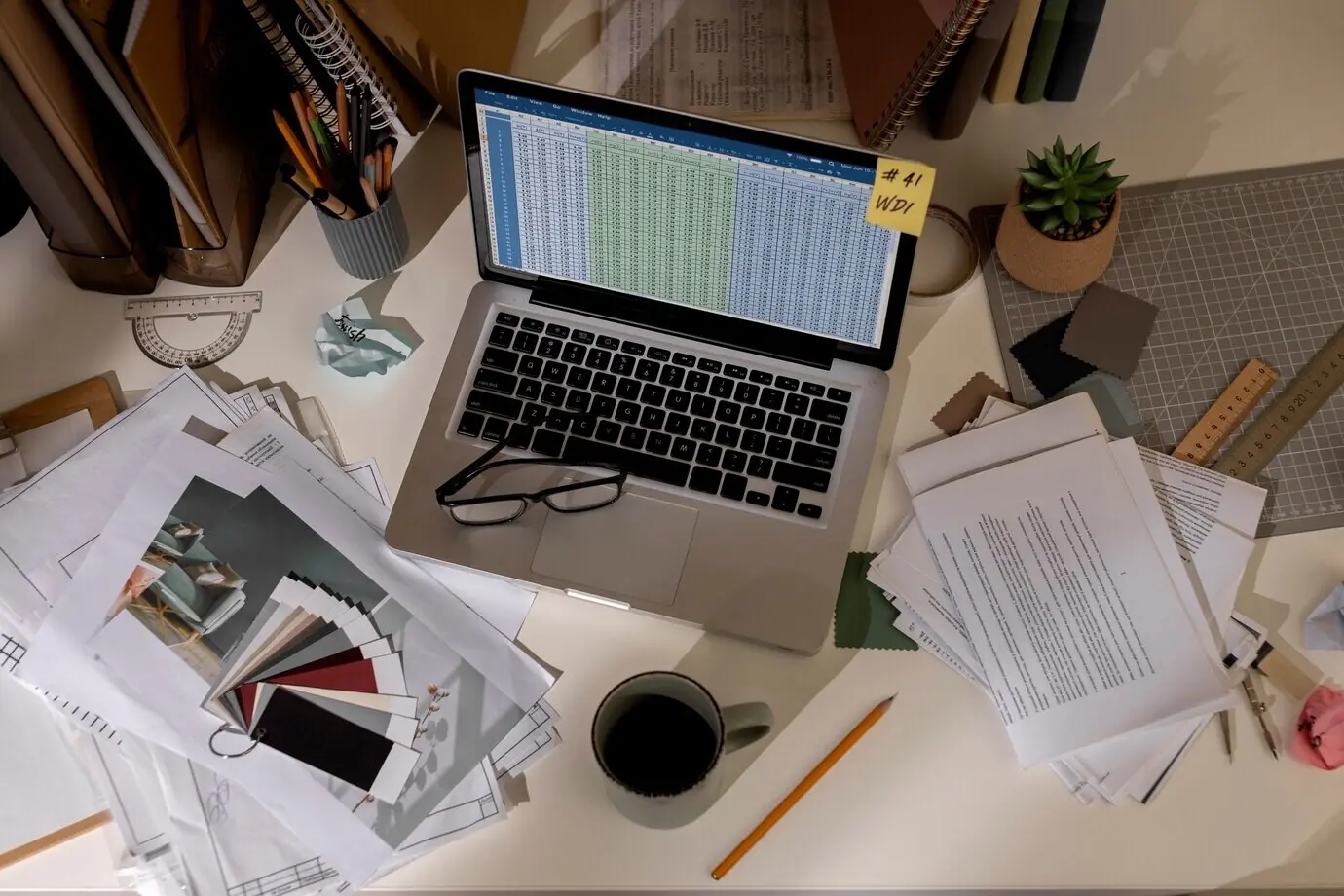 A view of a cluttered office work area with a laptop.